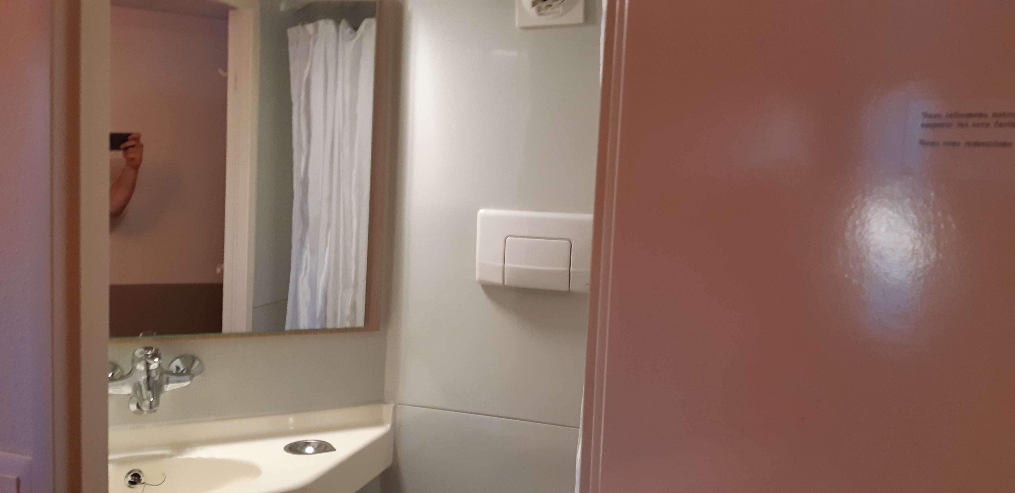 Un baño con lavamanos, espejo y cortina de ducha.