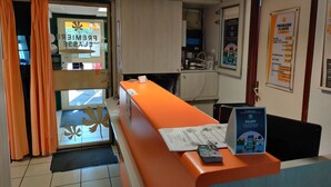 Ein Hotel-Empfangsbereich mit einer Rezeption, einem Computer und einem Plakat, das einen 5%-Rabatt auf alle Buchungen anbietet.