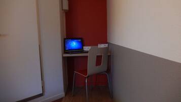 Um pequeno escritório com uma mesa, um laptop e uma cadeira.