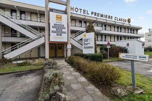 Entrada de un hotel con una escalera, un cartel de recepción y una señal que anuncia una opción económica.