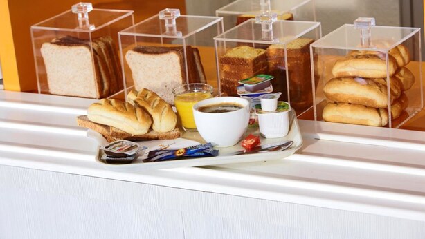 A breakfast display with various breads, pastries, and condiments in clear containers. - Premiere Classe Dunkerque Sud - Loon Plage (Loon-Plage)