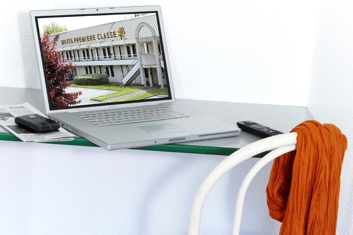 A laptop on a desk displaying a hotel named "HOTEL PREMIERE CLASSE" with a modern building exterior.