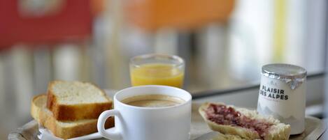 A breakfast tray with toast, a cup of coffee, a glass of orange juice, and a container of jam.
