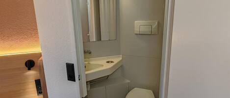 A compact bathroom with a toilet, sink, and mirror.