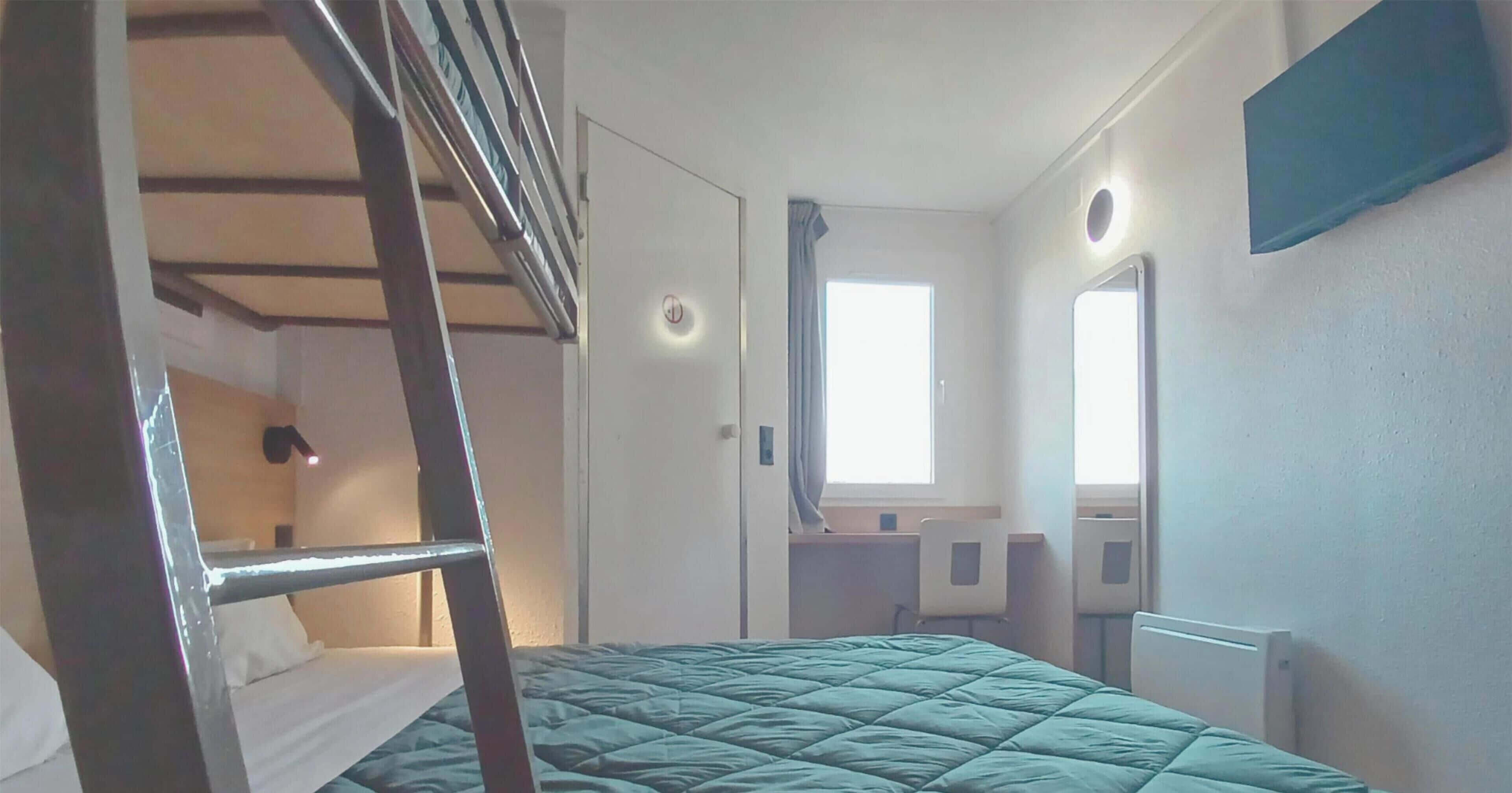 A room with a bunk bed, a desk, a chair, a window, and a radiator.