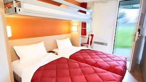 A hotel room with two beds, a red bedspread, a wooden headboard, a red chair, and a sliding glass door leading to a balcony. - Premiere Classe Metz Sud - Jouy-Aux-Arches (Jouy-aux-Arches)