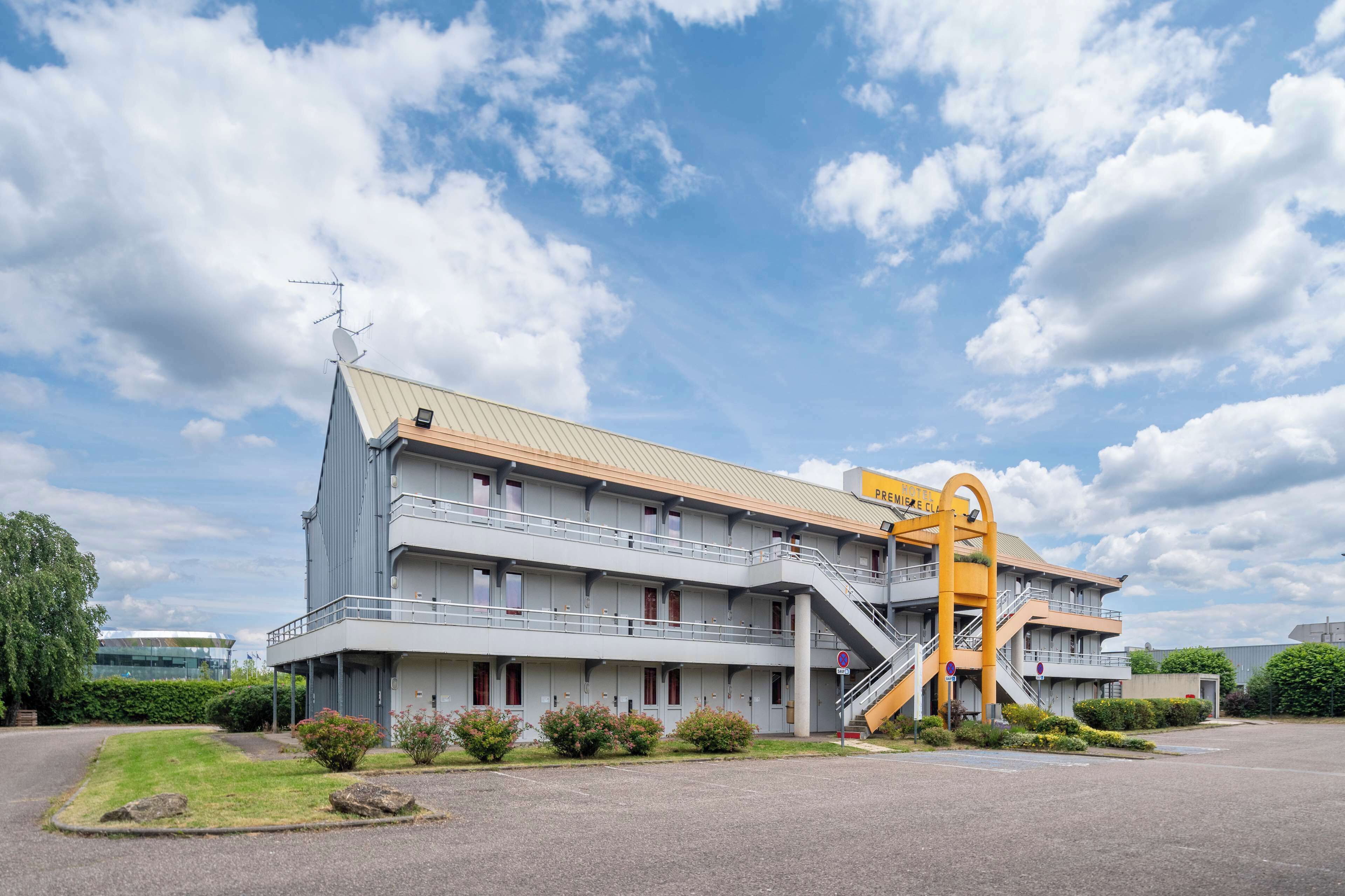 A multi-story hotel with a modern architectural design, featuring a prominent yellow spiral staircase and a flat roof.