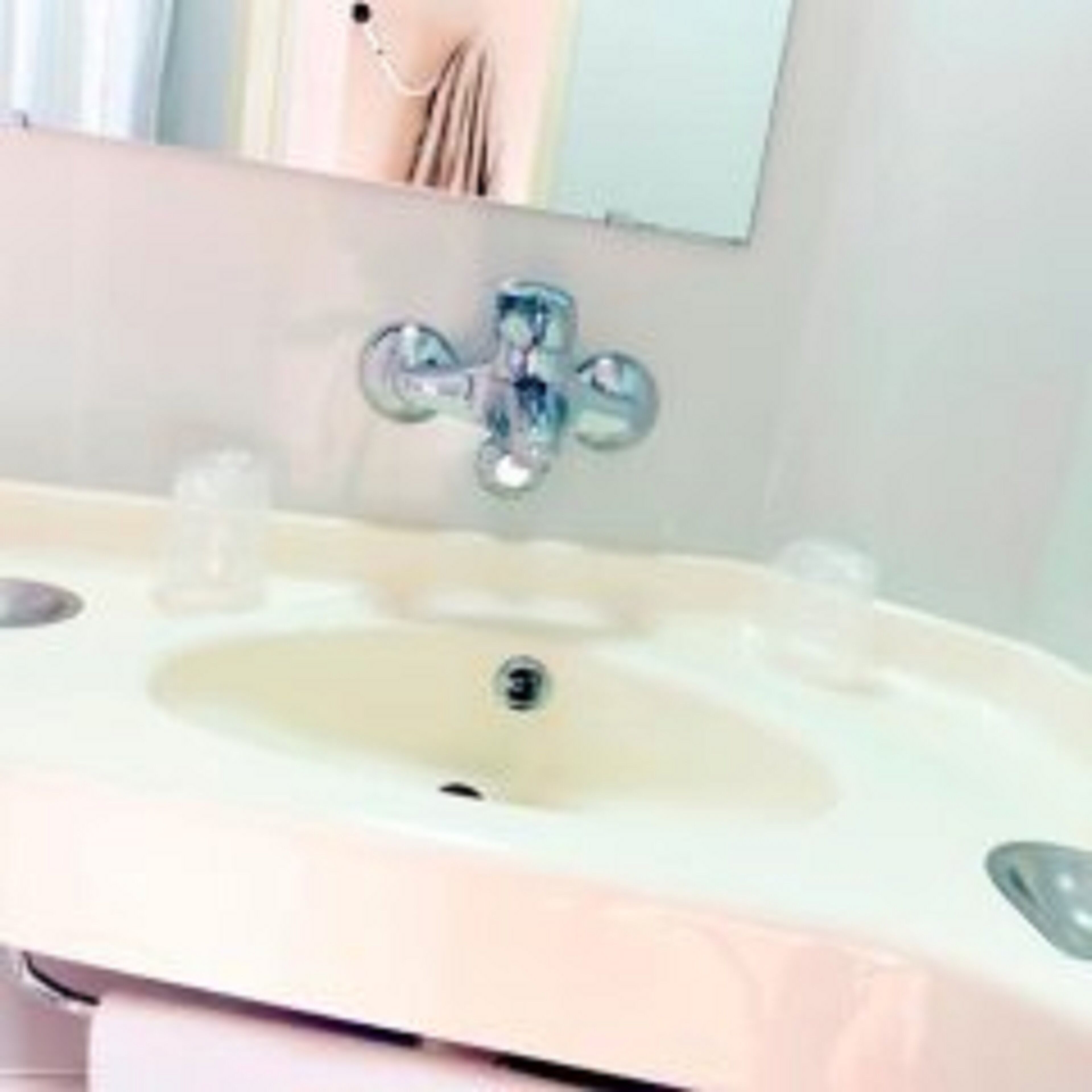 Ein Badezimmer mit einem weißen Waschbecken, einem Spiegel und einem Wasserhahn.