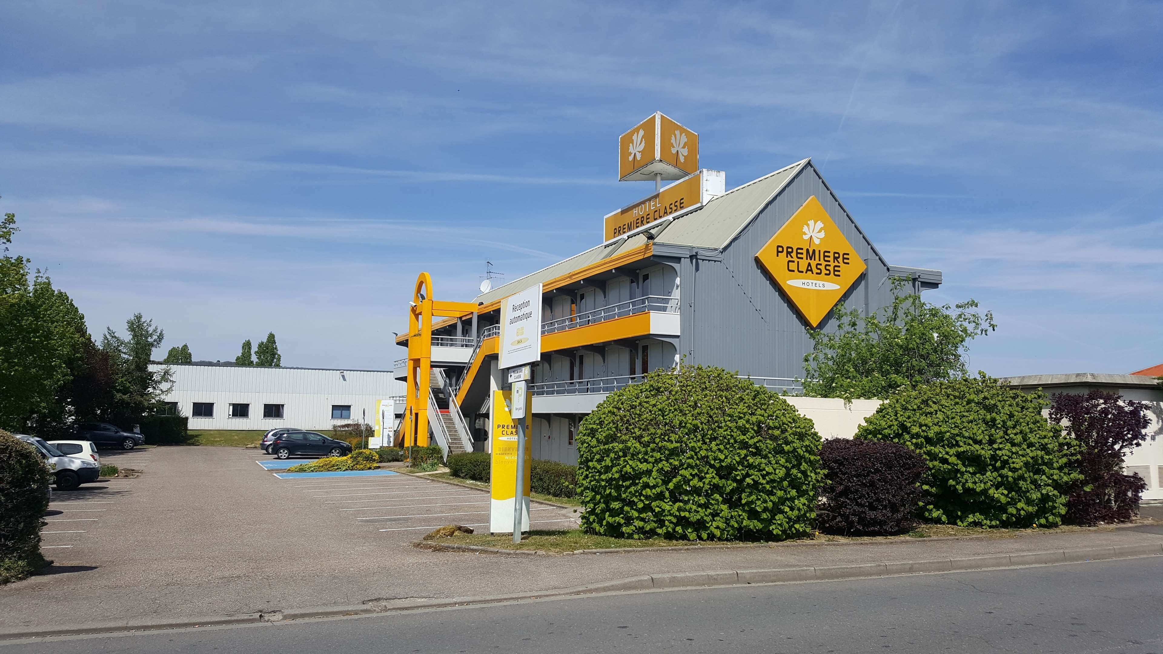 A hotel with a modern design, featuring a prominent 'Premiere Classe' sign and a reception area.