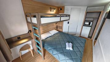 Un lit superposé avec un bureau et une chaise, un four à micro-ondes et un petit réfrigérateur dans une pièce de taille réduite.