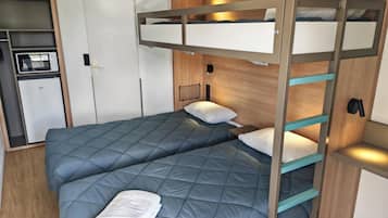 A bunk bed with a lower bed and a higher bunk, both with blue bedding. There is a white towel on the lower bed.