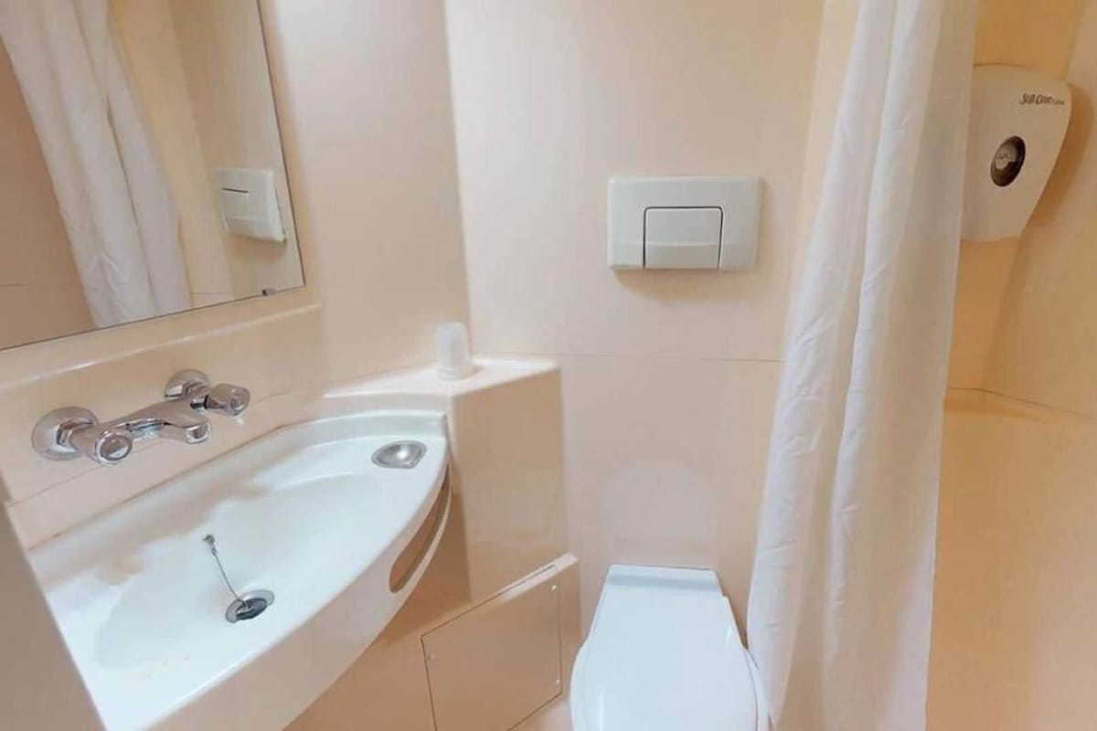 Een badkamer met een wastafel, spiegel, douchegordijn en toilet.