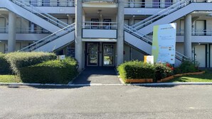 A multi-story building with a central entrance, staircases on either side, and a banner on the right.