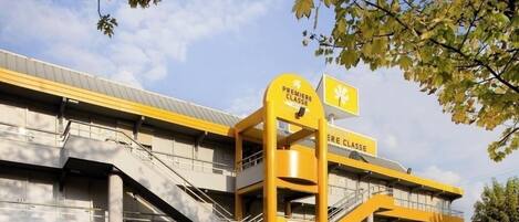 Ein Hotel mit Gelb-Weiß-Farbgebung, mit einer Treppe und Hinweisschildern mit den Aufschriften "Première Classe" und "Hotel".