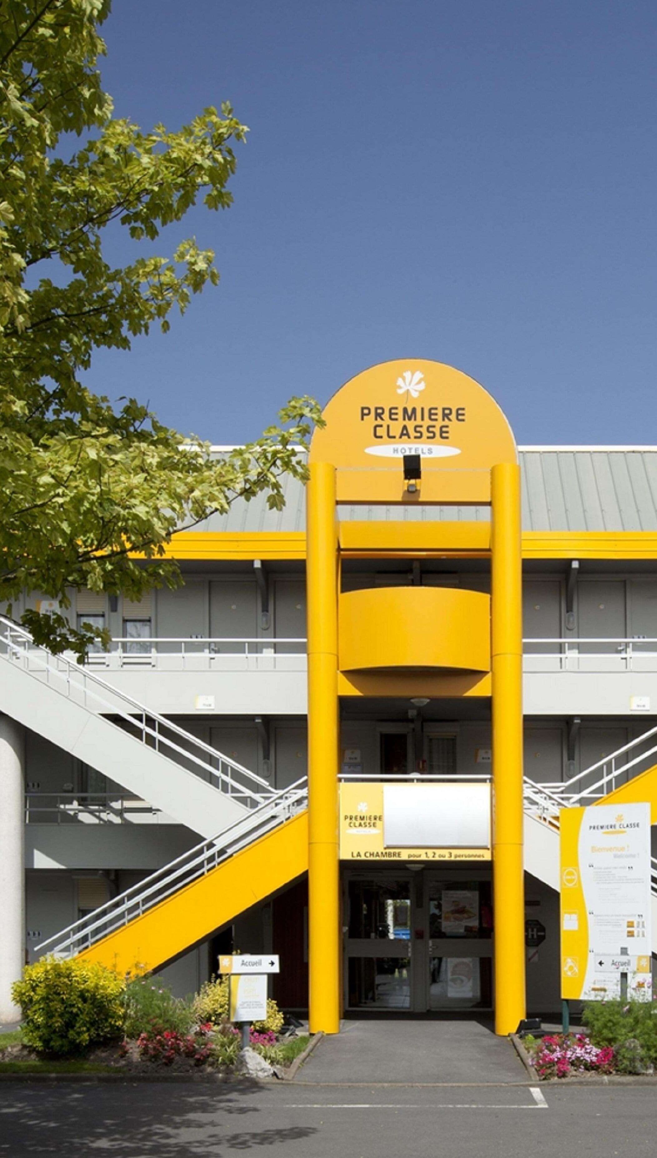 A hotel entrance with a prominent yellow archway and a staircase leading up to the entrance.