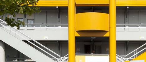 A hotel entrance with a prominent yellow archway and a staircase leading up to the entrance.