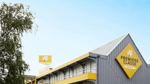 Ein Hotel mit einer markanten Fassade in Gelb und Grau, mit einem Schild, auf dem "Premiere Classe Hotels" steht.