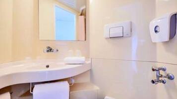 A modern bathroom with a large sink, a mirror, a towel rack, a soap dispenser, and a toilet.