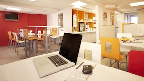 Ein moderner Essbereich mit Tischen, Stühlen und einem Laptop auf einem Tisch.