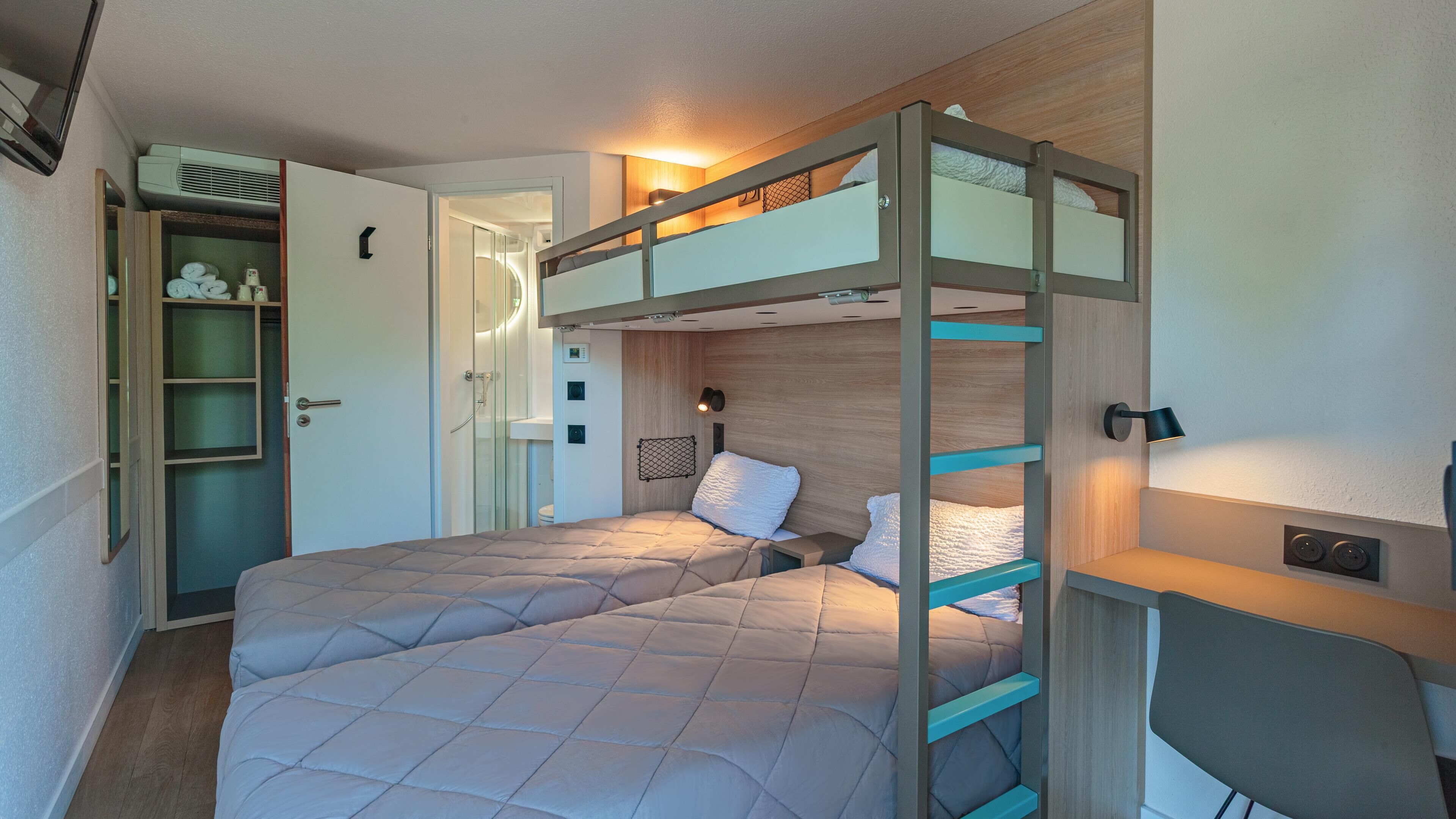 Habitación con literas, escritorio, armario y ducha.