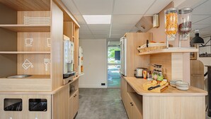 Una cocina moderna con armarios de madera, una cafetera, un tostador y un dispensador de fruta.