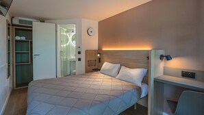 Un dormitorio con cama, mesita de noche, lámpara y un vestidor.