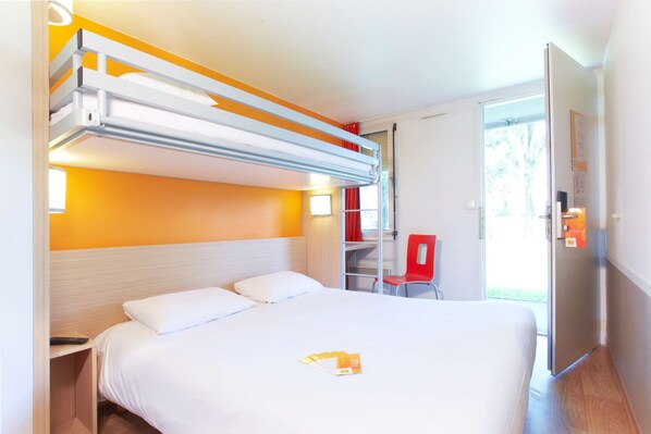A hotel room with a bunk bed, a single bed, a desk with a chair, and a door leading to a balcony. - Premiere Classe Bordeaux Sud-Pessac Becquerel (Pessac)