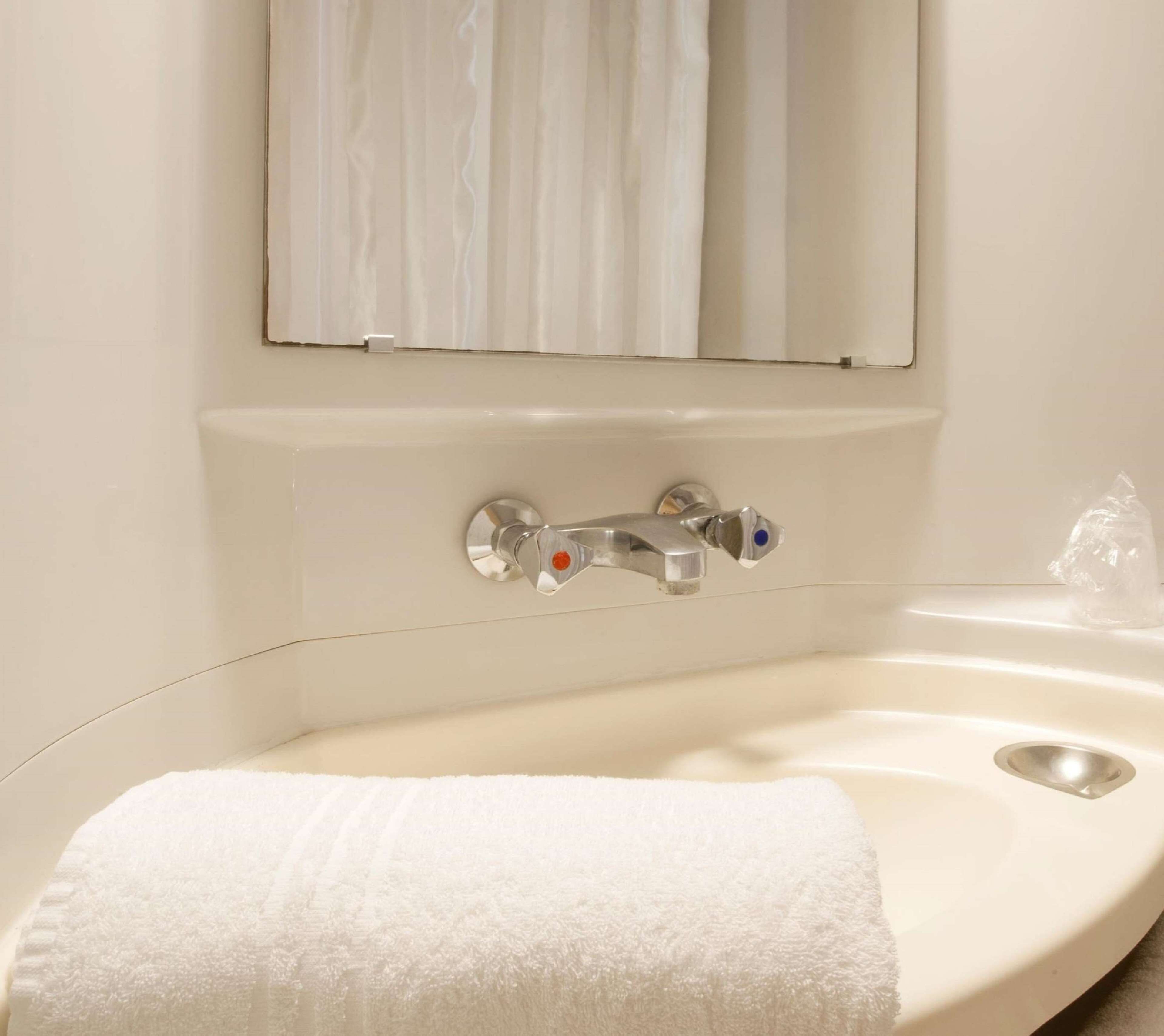 A bathroom with a bathtub, a sink, and a mirror.