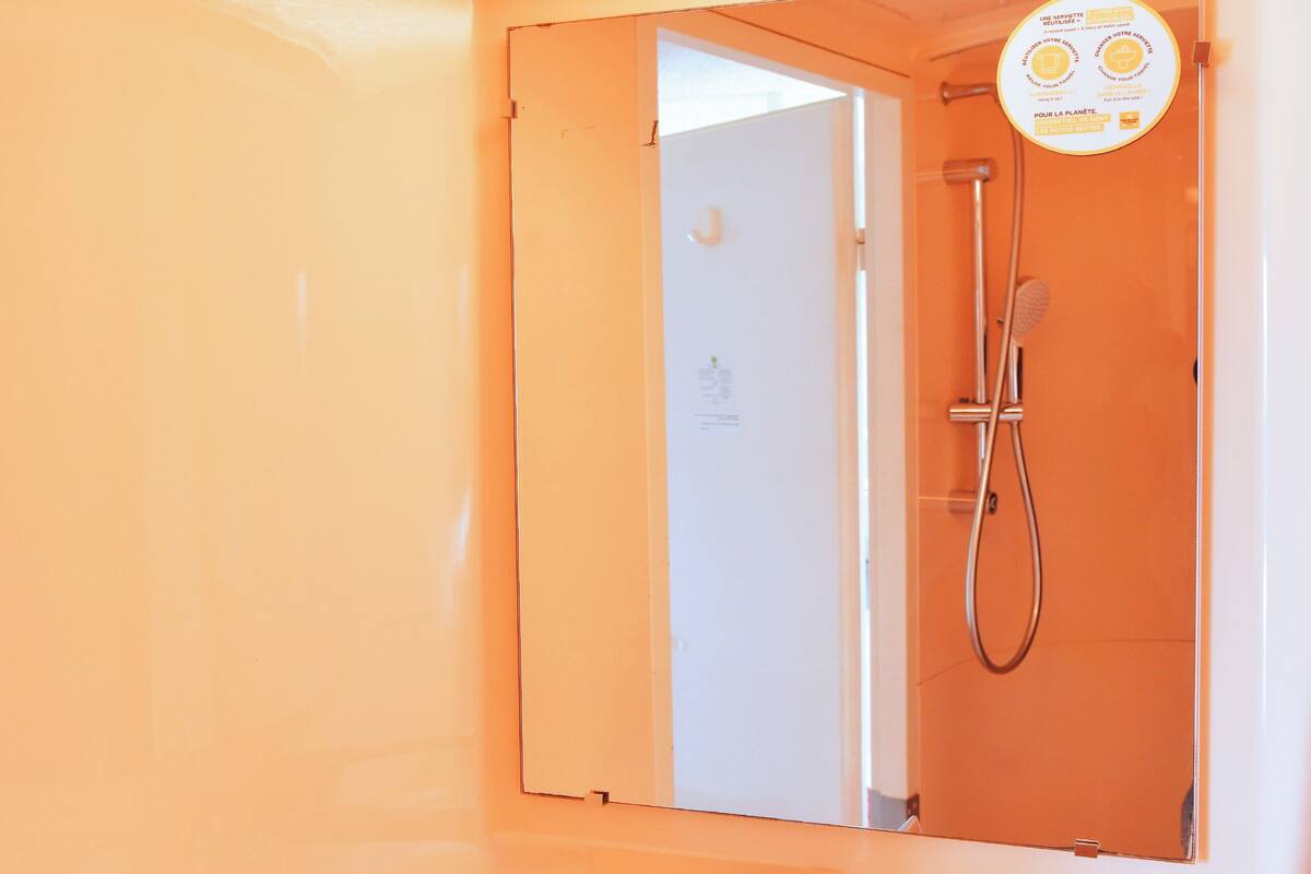 Une salle de bain avec un lavabo blanc, un miroir et une douche.