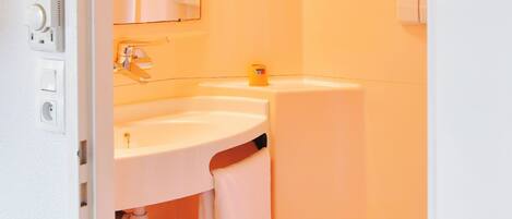 A bathroom with a white sink, mirror, and toilet.