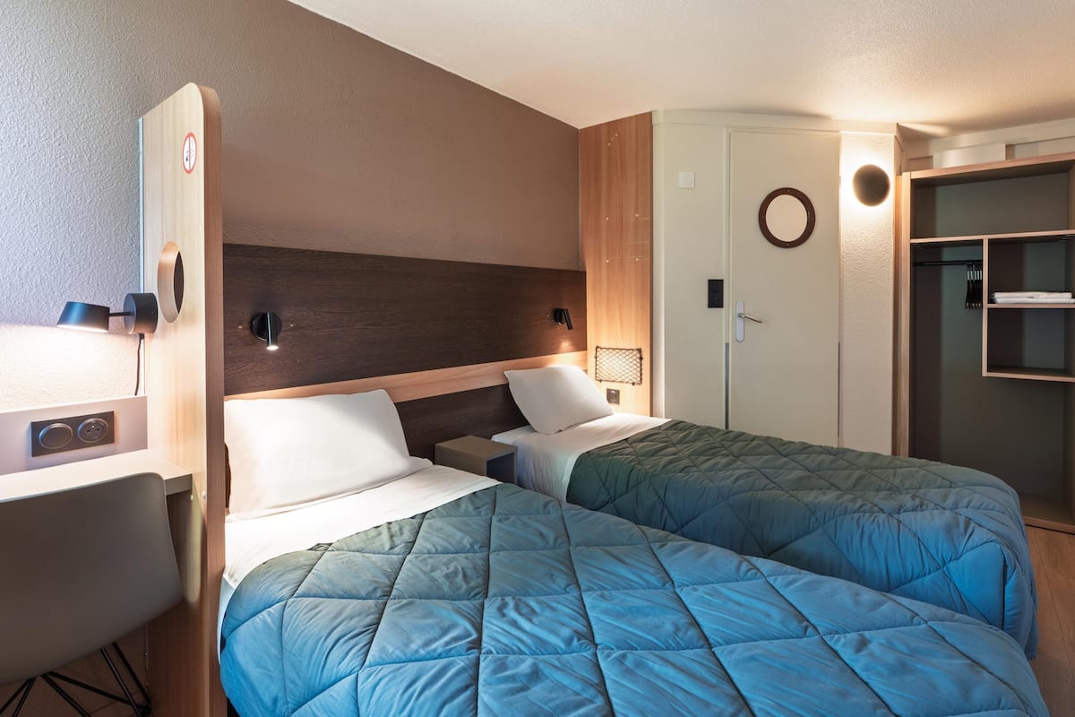 Une chambre d’hôtel avec deux lits, un bureau, une armoire et une salle de bain.