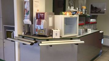 A self-service beverage station with a coffee machine, a microwave, and a refrigerator.