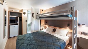 A compact hotel room with a bunk bed, a kitchenette, and a small desk.