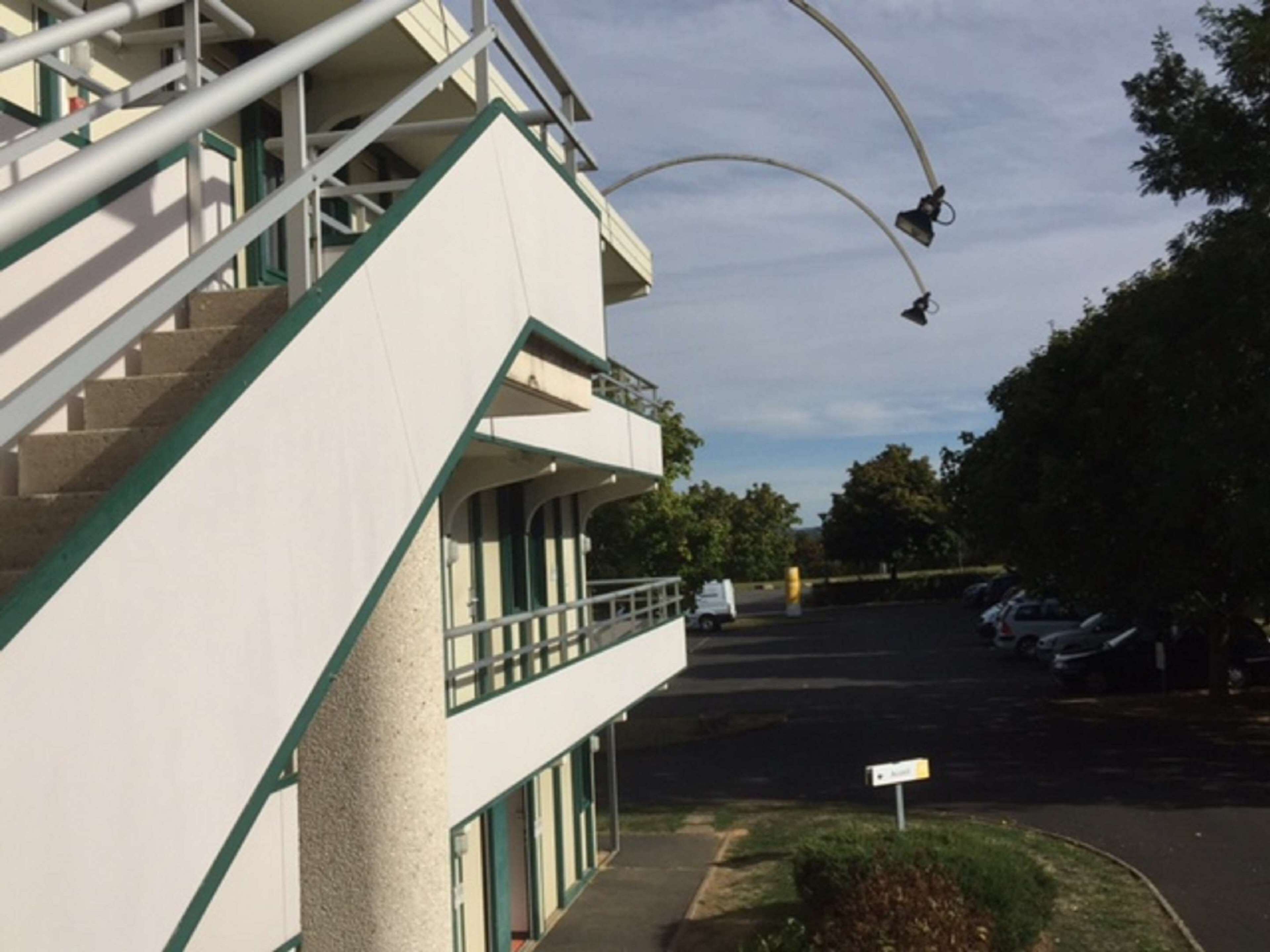A multi-story building with a staircase and a parking lot.