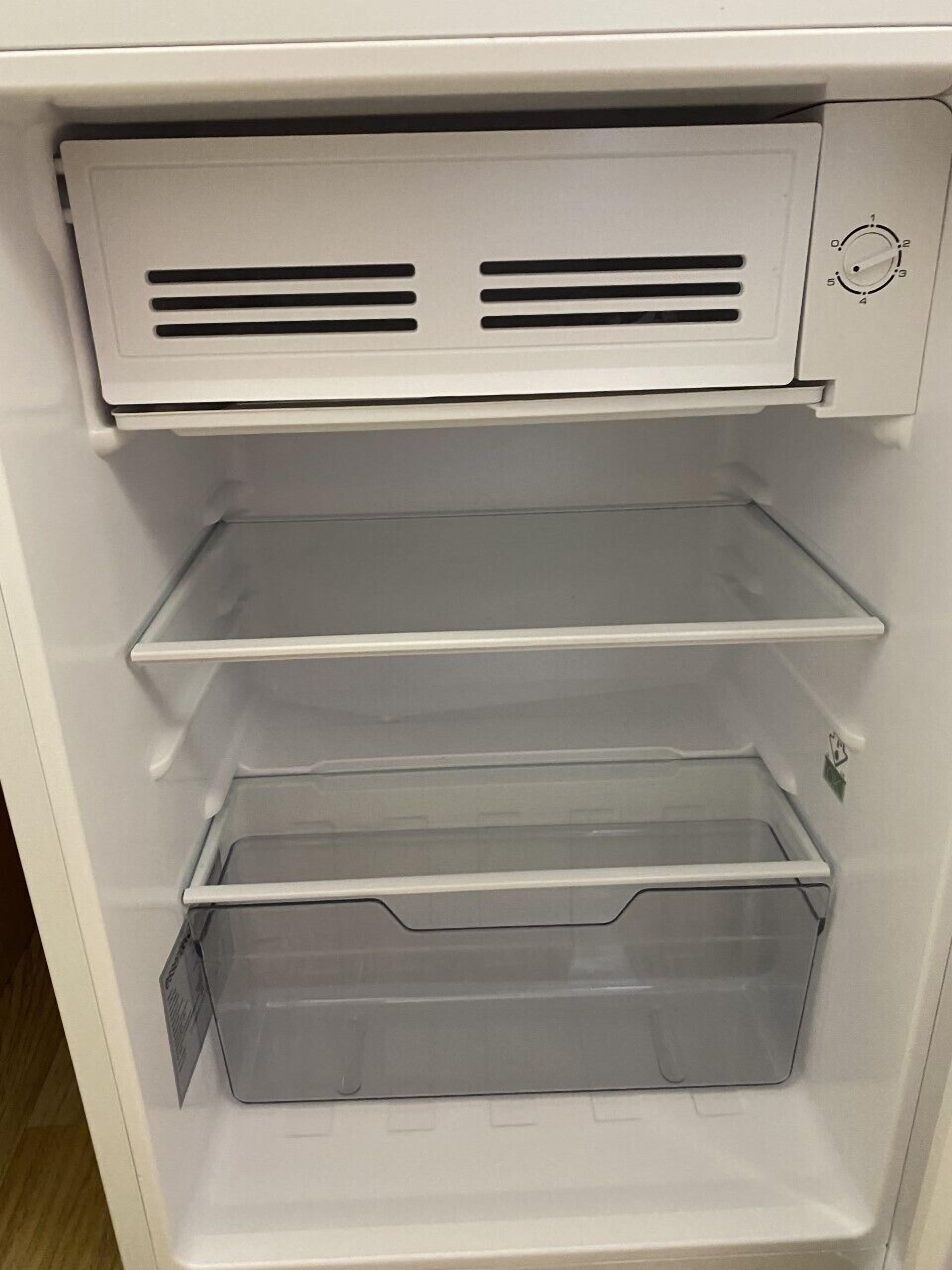 Un intérieur blanc avec trois étagères et un grand compartiment de rangement transparent.