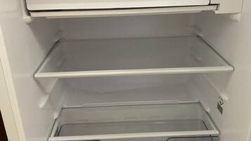 Un intérieur blanc avec trois étagères et un grand compartiment de rangement transparent.