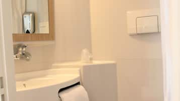 A bathroom with a sink, mirror, toilet, and a towel rack.