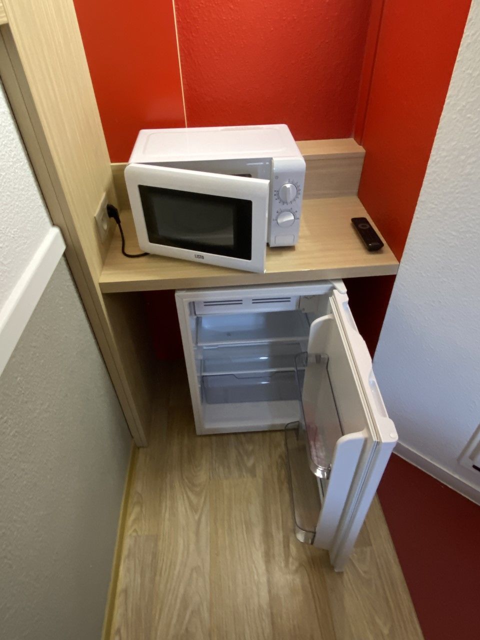 A compact kitchenette with a microwave and a small refrigerator.