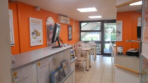 Un área de recepción con mostrador, sillas y carteles informativos.