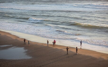 A beach with people walking along the shore.