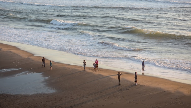 Een strand met mensen die langs de kust wandelen.