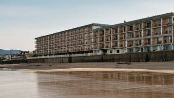 Un hôtel à plusieurs étages, doté de balcons, situé près d’une plage.