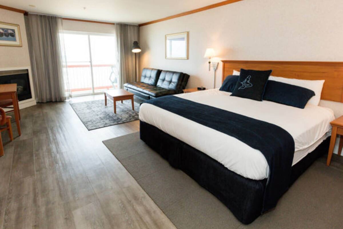 Une chambre d’hôtel avec un grand lit, un canapé, un bureau et une cheminée.