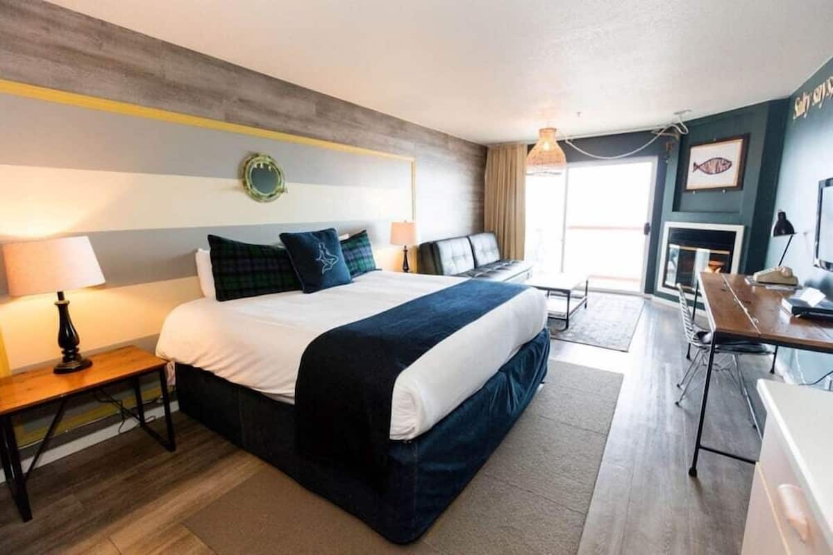 Une chambre d’hôtel avec un lit, des tables de chevet, un bureau et une chaise.