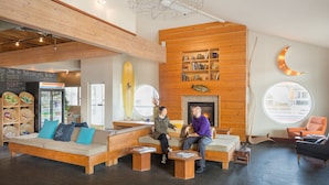 Een knusse lobby met een houten receptiebalie, een open haard en een groot raam met uitzicht.