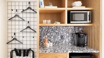 A compact kitchen with a microwave, coffee maker, and a small cabinet.