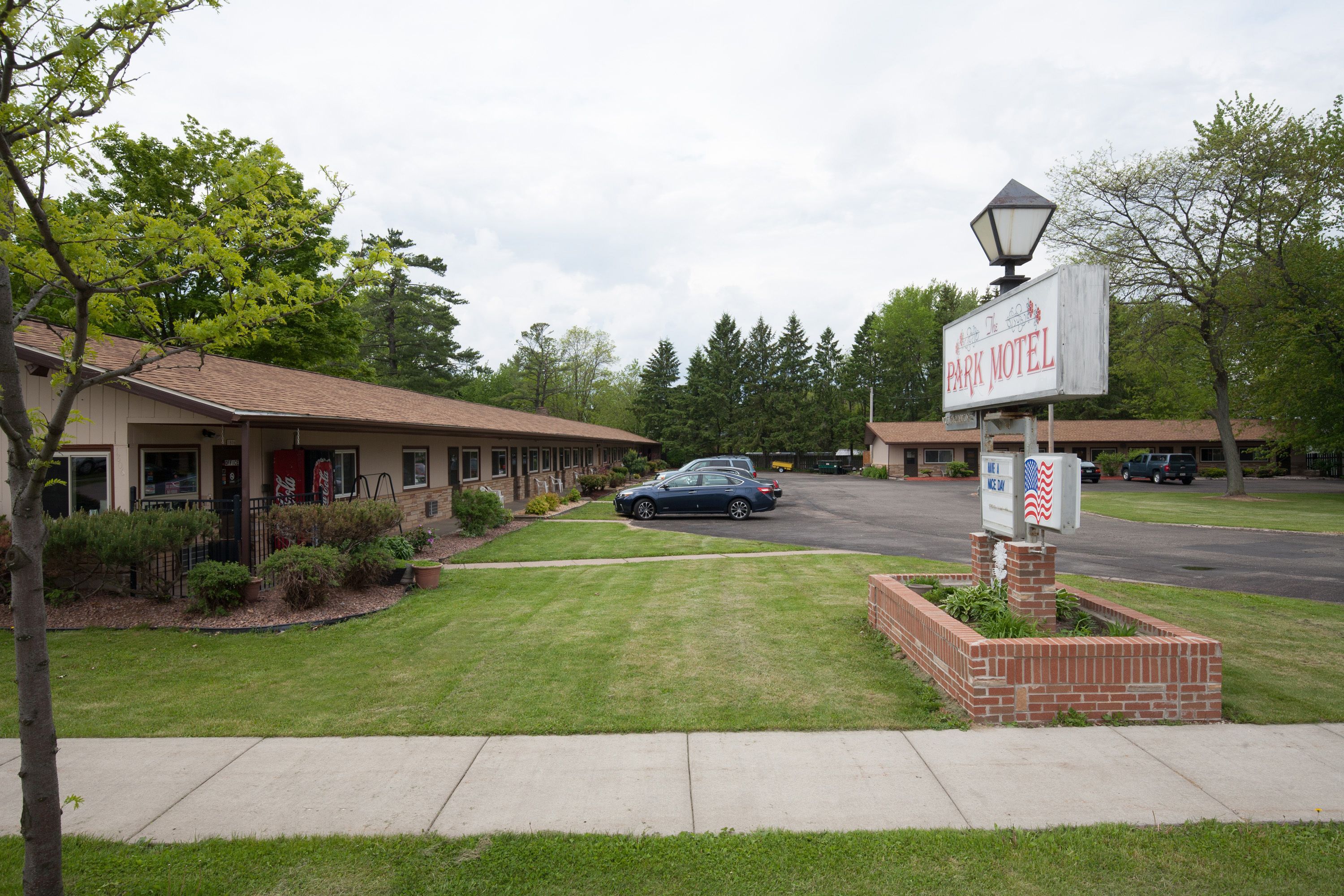 Ett motell med en skylt där det står ”Park Motel” och en blomlåda av tegel med en amerikansk flagga.