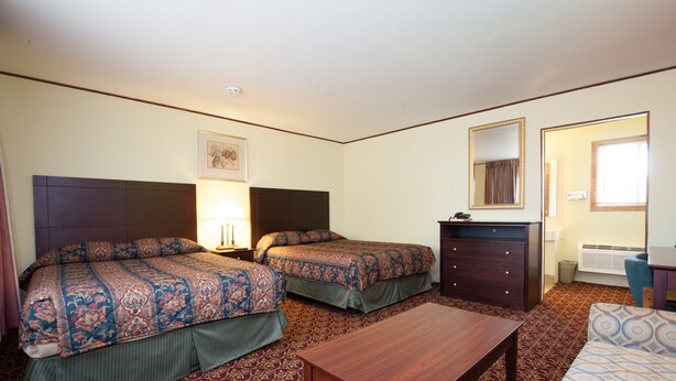 Habitación de hotel con dos camas, una mesa de madera, un aparador y un espejo.