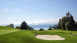 Un parcours de golf offrant une vue dégagée sur un lac et des montagnes au loin.