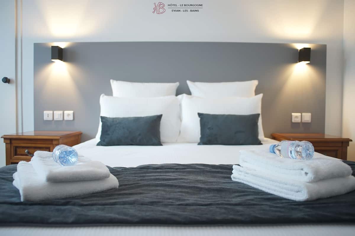 A hotel room with a large bed, two nightstands, and a headboard with wall-mounted lighting.